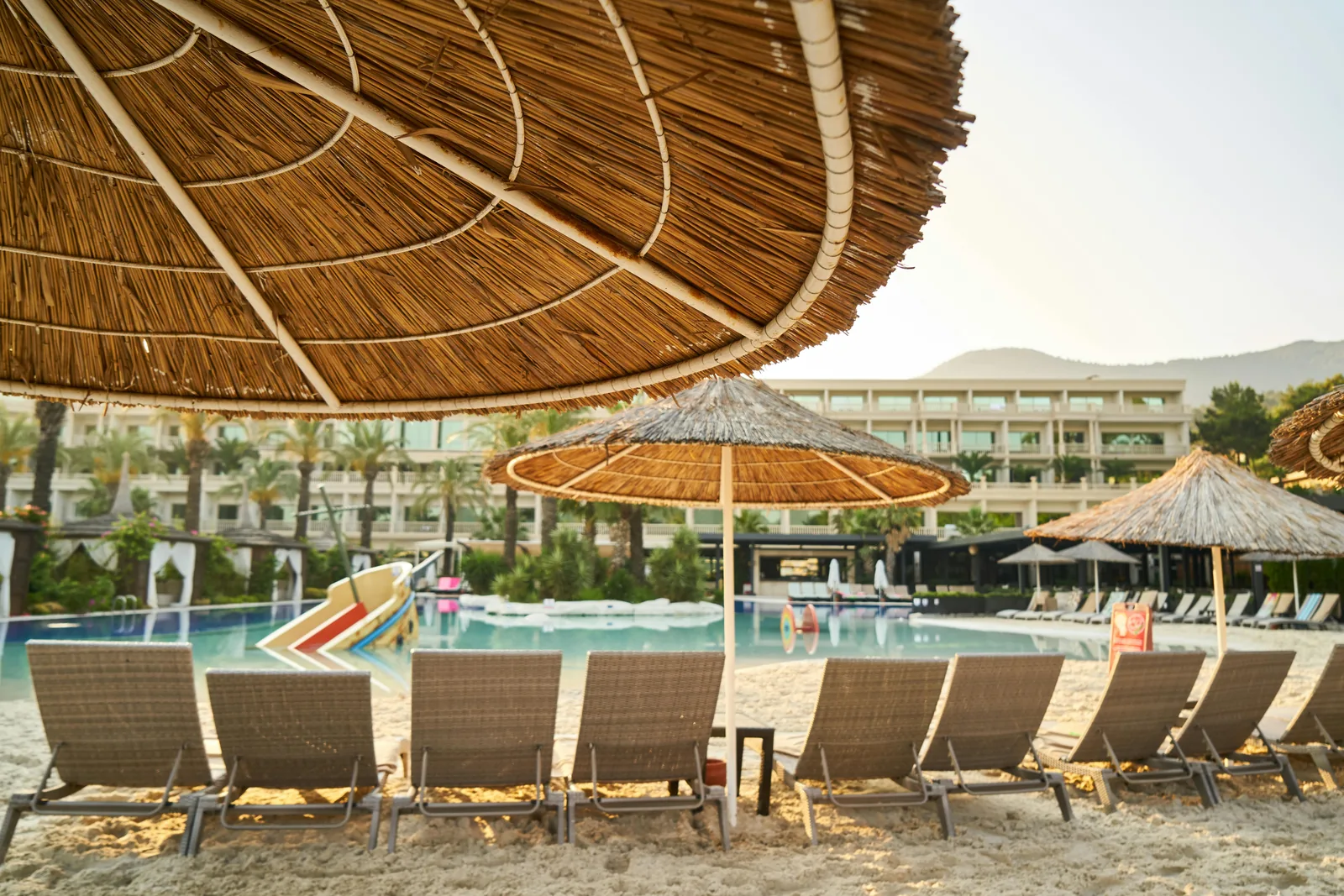 Beachfront resort with pool loungers and umbrellas.