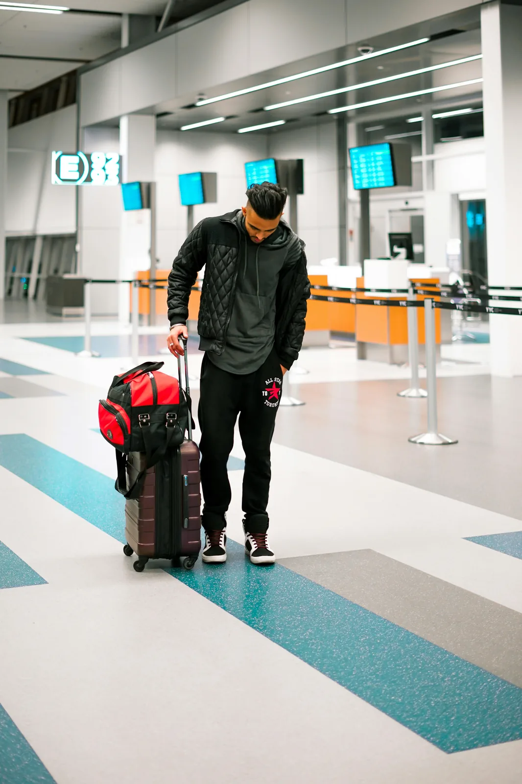 Traveler standing with luggage at an airport terminal.